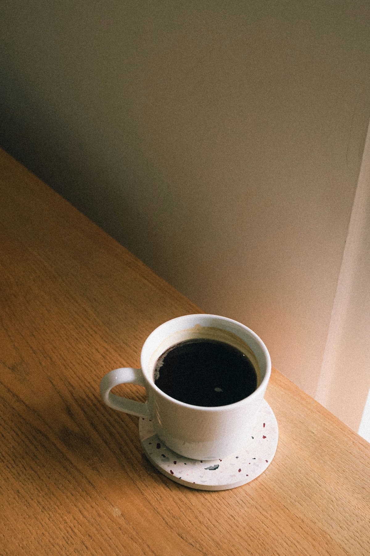 木のテーブルに置かれたブラックコーヒーのカップ